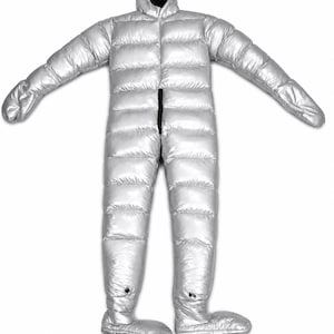 Op de afbeelding: Een metallic zilveren, gewatteerd jumpsuit voor het hele lichaam met een aangehechte capuchon met zwarte binnenvoering, lange mouwen met geïntegreerde wanten en vaste voetbedekkingen. Een verticale zwarte rits loopt over het midden.