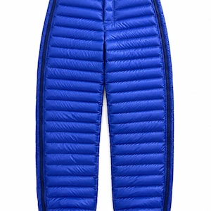 Peut inclure: Pantalon en duvet matelassé bleu vif avec une construction à compartiments horizontaux, une fermeture centrale à bouton-pression à la taille et des fermetures éclair verticales sur toute la longueur des coutures extérieures, finissant par des ourlets élastiqués.