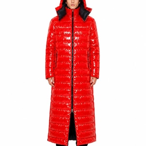 May include: A long, bright red puffer coat with a glossy, patent-like finish. This full-length quilted jacket features a high collar, a hood with a black interior lining, and a central black zip that runs the entire length of the garment.