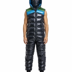 Puede incluir: Un mono sin mangas de plumón negro brillante y acolchado, con cremallera frontal completa, capucha con máscara facial integrada y paneles de colores azul brillante y verde en la parte superior del pecho y la capucha.