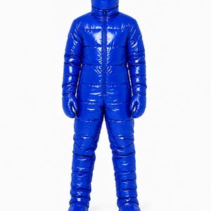 Op de afbeelding: Een volledig gewatteerd jumpsuit in felblauw met een glanzende, lakachtige afwerking. Het kledingstuk is voorzien van een capuchon met hoge kraag en een donker geïntegreerd vizier, lange mouwen met bijpassende wanten en broekspijpen.