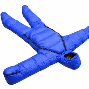 Op de afbeelding: Een felblauwe, geïsoleerde draagbare slaapzak met een capuchon, geïntegreerde mouwen en beensecties. Het kledingstuk is voorzien van zwarte ritssluitingen die diagonaal over de romp en langs het onderste beengedeelte lopen.