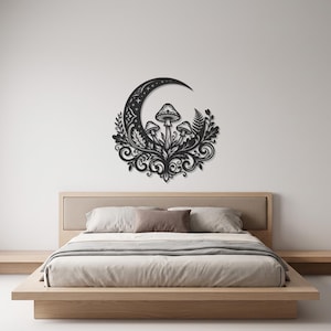 May include: A black metal wall art piece featuring a crescent moon shape adorned with three mushrooms, intricate swirling vine patterns, and fern-like leaves. The design is symmetrical and detailed, showcasing a cutout silhouette style.