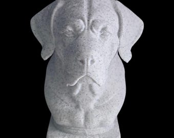 Puede incluir: Una escultura detallada y moteada, de color gris claro, de la cabeza y la parte superior del cuerpo de un perro. El perro tiene orejas caídas y una expresión suave. La escultura está montada sobre una base rectangular, sobre un fondo negro.
