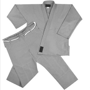 May include: A solid gray martial arts uniform consisting of a long-sleeved jacket with a thick lapel and matching pants. The pants feature a white drawstring at the waist. Both pieces are constructed with reinforced stitching along the seams.