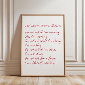 May include: A rectangular framed wall art piece featuring red handwritten text on a white background. The text reads: MY HOME OFFICE RULES. Do not ask if I'm working. Yes, I'm working. Do not ask what I'm doing. I'm working. Do not ask if I'm done. I'm not done. Do not ask for a favor. I am literally working.