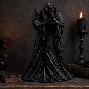 May include: A black sculpture depicting two hooded figures in long, flowing robes standing close together. The figures are draped in dark fabric with visible folds and textures, appearing to hold hands in a dance-like pose with obscured faces.