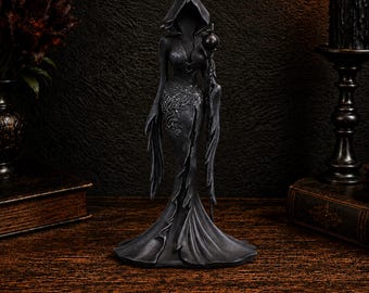 Könnte beinhalten: Eine dunkelgraue, kapuzentragende Figur einer schlanken Gestalt in einem langen, fließenden Gewand. Das Kleid ist mit detaillierten, erhabenen silberfarbenen Blumenranken verziert und die Figur hält einen dünnen Stab mit einer runden Kugel an der Spitze.