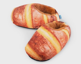 May include: A pair of plush slippers designed to resemble golden-brown baked bread loaves. The exterior features a realistic print of a crusty baguette with light and dark brown tones, while the interior is lined with soft, fuzzy brown fabric.