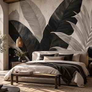 Puede incluir: Un dormitorio con un gran mural de pared con hojas de palmera tropicales de gran tamaño en negro y gris claro. La cama tiene un cabecero tapizado en beige, ropa de cama de colores claros y una manta de color gris oscuro al pie de la cama.