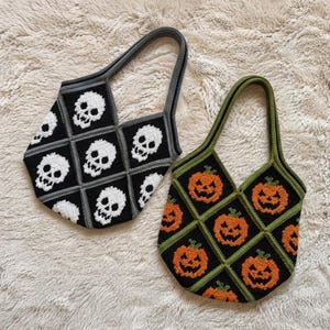 Peut inclure: Deux sacs fourre-tout en crochet avec des motifs en losange. Le sac de gauche est noir avec des motifs de crânes blancs et une bordure grise. Le sac de droite est noir avec des motifs de citrouilles orange et une bordure verte.