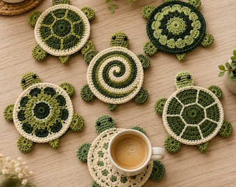 May include: A collection of six handmade crochet turtle coasters in various shades of green and cream. Each coaster features a circular shell design with small heads and flippers. One coaster is topped with a white ceramic mug filled with coffee.