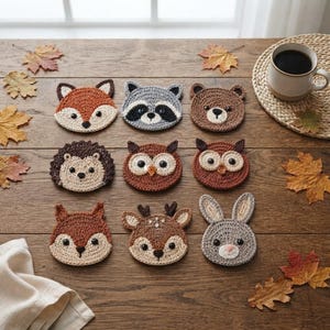 May include: A set of nine round crochet coasters featuring various woodland animal faces including a fox, raccoon, bear, hedgehog, two owls, squirrel, deer, and rabbit, each crafted with detailed yarn stitching and small dark eyes.