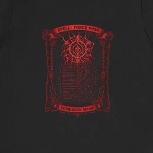 Op de afbeelding: Een zwart t-shirt met korte mouwen en een rode grafische print op de borst. Het ontwerp bevat een cirkelvormig embleem, verticale tekst en de woorden "SPELL: FORCE PUSH" bovenaan en "FORBIDDEN MAGIC" onderaan, binnen een rechthoekige rand.