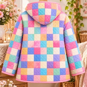 Peut inclure: Une veste &agrave; capuche matelass&eacute;e pr&eacute;sentant un motif &agrave; damier multicolore vif dans des tons de rose, bleu, jaune, vert et violet. Le v&ecirc;tement poss&egrave;de des manches longues, une capuche et un liser&eacute; rose uni le long des bords et de l'ourlet.