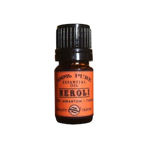 May include: A small amber glass bottle with a black cap. The label is orange and says "100% Pure Essential Oil Neroli Citrus Aurantium - Tunisia Quality Tested".