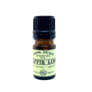 May include: A small amber glass bottle of essential oil with a black cap. The label reads "100% Pure Essential Oil" and "Kaffir Lime". The bottle is labelled "Citrus Hystrix" and "Indonesia".