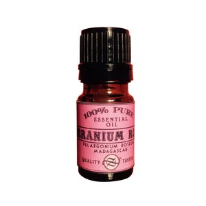 May include: A small, dark brown glass bottle with a black cap. The bottle is labeled "100% Pure Essential Oil Geranium Rose Pelargonium Roseum Madagascar Quality Tested".