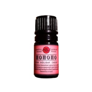 May include: A small, dark brown glass bottle with a black cap. The label is red and says "HOHOHO FOR HOLIDAY CHEER" with a list of essential oils included in the blend.