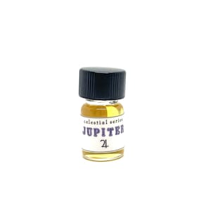 May include: A small, clear glass bottle with a black cap. The bottle contains a yellow liquid and has a white label that reads "celestial series JUPITER 24".