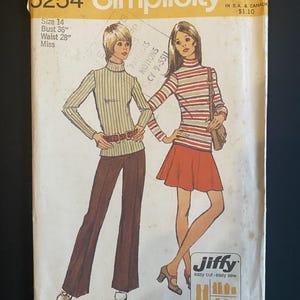 May include: A vintage Simplicity sewing pattern envelope number 5254 for size 14, featuring illustrations of two figures wearing turtleneck tops, one with striped trousers and one with a skirt. The yellow and white paper packet includes text.