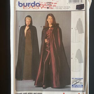 May include: A Burda Easy sewing pattern envelope, number 2566, featuring illustrations of two floor-length capes. Style A is a black hooded cape, and style B is a dark red cape with a collar. The envelope includes sizing charts and text.