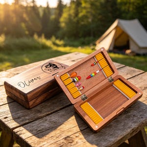 May include: A rectangular wooden fly fishing box with a hinged lid, featuring the name Oliver and a fish graphic engraved on the exterior. The open interior contains yellow foam inserts and several colorful fishing flies with hooks.