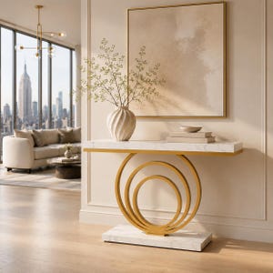 May include: A console table featuring a white marble-patterned rectangular top and base, connected by three concentric gold-toned metal circular rings. The table holds a white ribbed vase with delicate green branches and two stacked books.