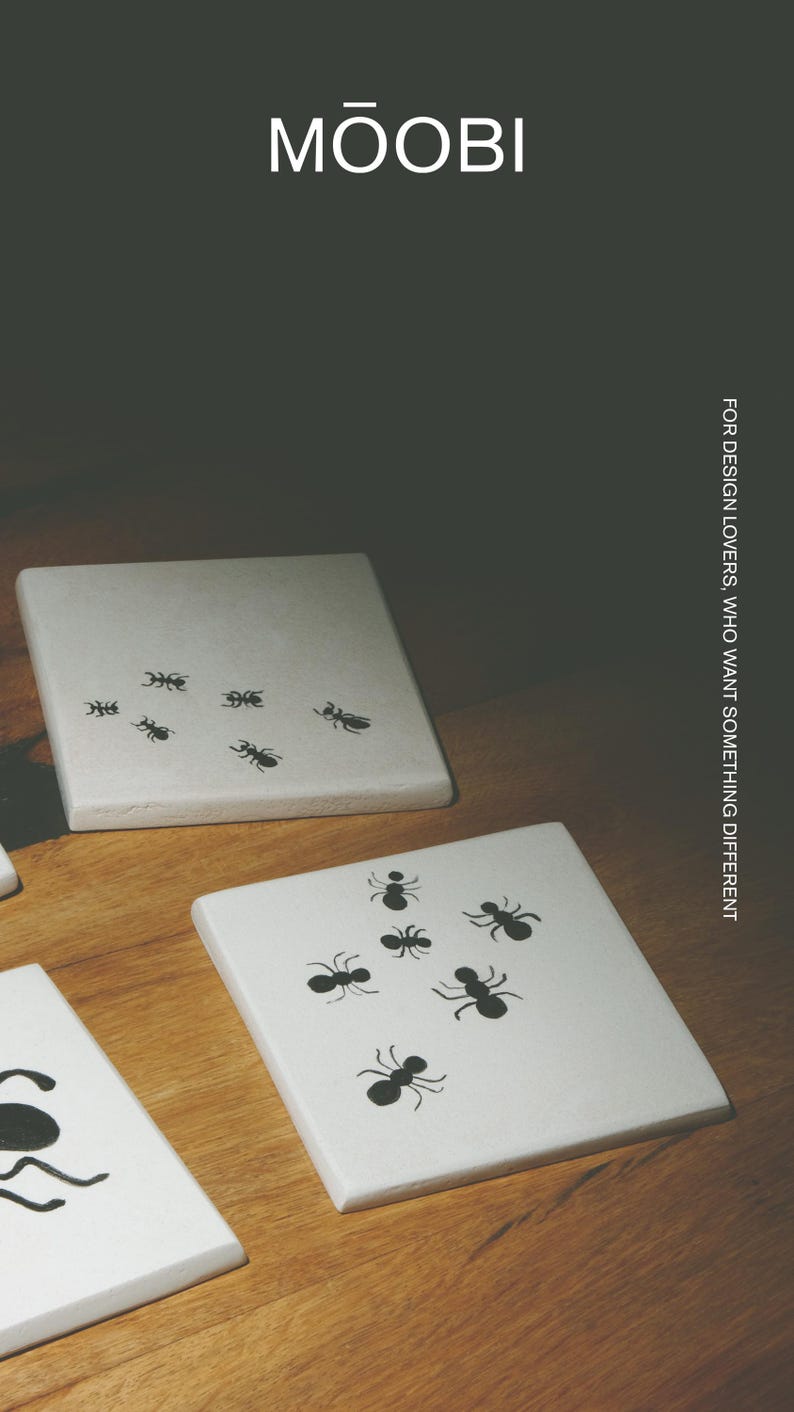 Pu&ograve; includere: Sottobicchieri quadrati bianchi con illustrazioni di formiche nere. Il testo MŌOBI e FOR DESIGN LOVERS, WHO WANT SOMETHING DIFFERENT sono visibili. I sottobicchieri hanno una superficie liscia e sono disposti su una superficie in legno. Ogni sottobicchiere mostra un motivo unico di piccole formiche nere.