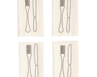 Puede incluir: Un juego de cuatro servilletas de tela de color blanco roto, cada una con un contorno bordado en negro de un tenedor y un cuchillo colocados uno al lado del otro. El bordado utiliza una puntada simple para definir las formas de los cubiertos.