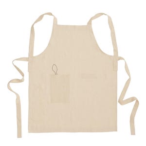 May include: A beige apron featuring two front pockets and long waist ties. The left pocket displays a small, dark, embroidered outline of a spoon. The apron has a square neckline and two shoulder straps that extend to the sides for fastening.