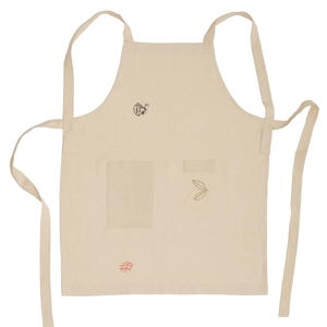 May include: A beige apron featuring two front pockets and thin fabric ties. The apron is decorated with small, delicate embroidered line art designs, including a black butterfly, a red beetle, and a simple golden leaf motif on the front panel.