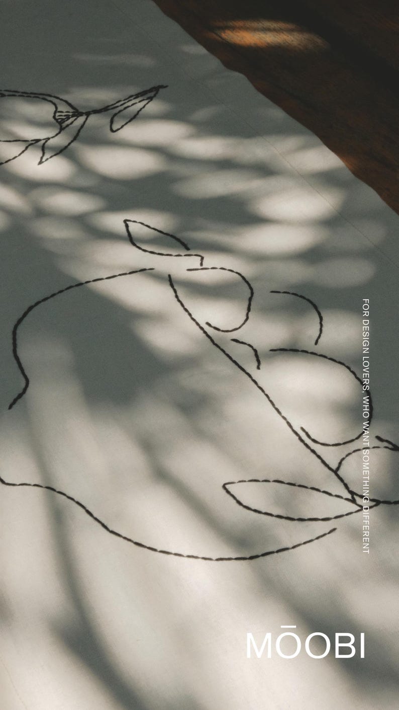 Pu&ograve; includere: Un tessuto bianco con ricami neri che raffigurano disegni botanici a linee. Il tessuto riporta il testo "FOR DESIGN LOVERS, WHO WANT SOMETHING DIFFERENT" e il nome del marchio "MOOBI" stampato in bianco nell'angolo in basso a destra.