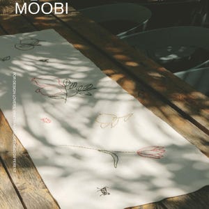 May include: A rectangular off-white table runner featuring delicate line-art embroidery of various botanical elements and small insects in black and red thread. The text MOOBI and FOR DESIGN LOVERS, WHO WANT SOMETHING DIFFERENT is printed on the runner.
