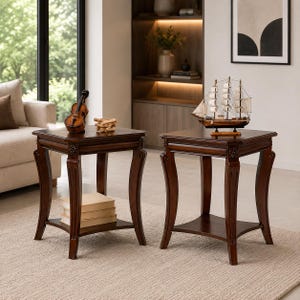 May include: Two square dark brown wooden end tables featuring curved legs and a lower shelf. One table holds a small violin model and a stack of books, while the other supports a detailed model ship with white sails on a wooden base.
