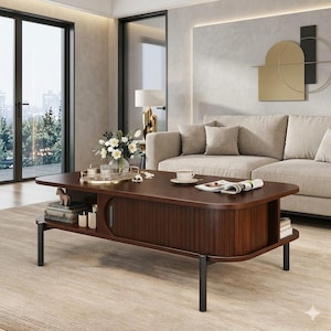May include: A dark brown wooden coffee table with rounded edges, featuring a central sliding tambour door, open side shelving, and four slender black metal legs. The tabletop holds a gold-rimmed tray with a vase of white flowers and a cup.