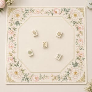 May include: A square mahjong mat with a cream-coloured surface featuring a border of pink peonies and green foliage. The mat has a thin gold octagonal frame printed in the centre, with five scattered mahjong tiles displaying various gold designs.