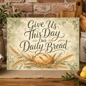 Puede incluir: Un letrero rectangular con el texto "Give Us This Day Our Daily Bread" en letra cursiva de color marrón oscuro. El fondo es una mezcla de estilo acuarela en verde salvia y crema, decorado con ilustraciones de espigas de trigo doradas y un pan.
