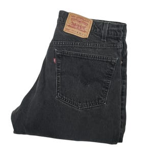 Könnte beinhalten: Schwarze Jeans aus Denim mit einem beigen Lederaufnäher am hinteren Bund, der den Text Levi Strauss & Co. 550 W 38 L 30 trägt. Die Jeans verfügt über eine Gesäßtasche mit einem kleinen roten Etikett und klassischen Ziernähten.