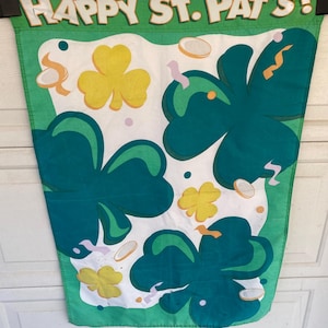 May include: A green and white St. Patrick's Day banner with the words "HAPPY ST. PAT'S!" in white letters. The banner features large green shamrocks, yellow shamrocks, and gold coins.