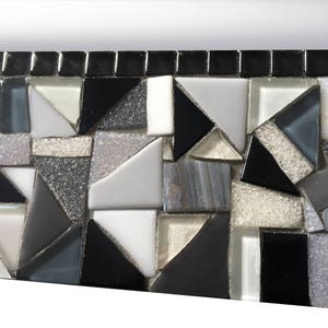 Puede incluir: Primer plano de un borde de mosaico hecho de peque&ntilde;os cuadrados y tri&aacute;ngulos negros, blancos y grises. Los azulejos de mosaico est&aacute;n dispuestos en un patr&oacute;n geom&eacute;trico.