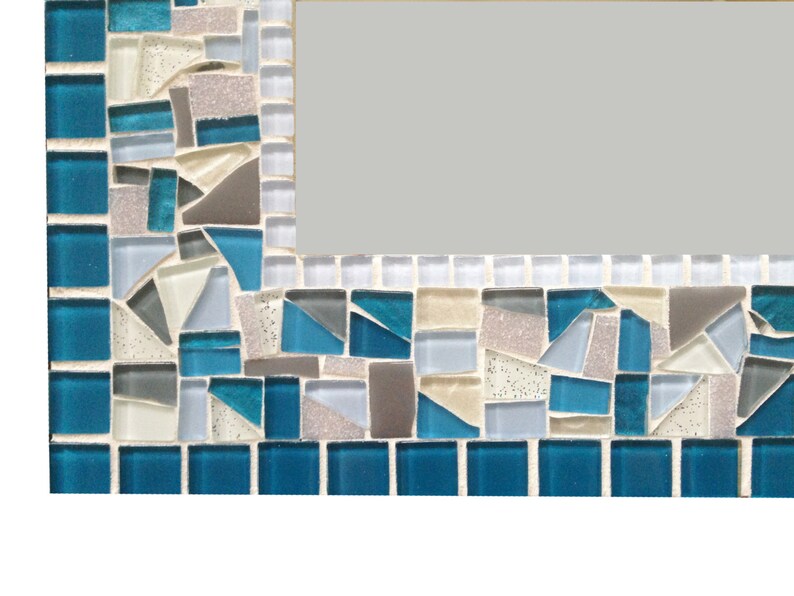 A mosaic mirror frame with a blue, white, and gray color scheme. The mosaic frame is made of small, irregular shaped, hand cut glass tiles.