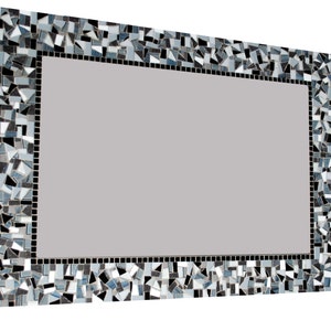Puede incluir: Un espejo rectangular con un marco decorativo hecho de peque&ntilde;as piezas irregulares de mosaico negro, blanco y gris.