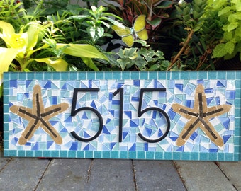 May include: A blue and white mosaic house number sign with black numbers "515" and two brown starfish.