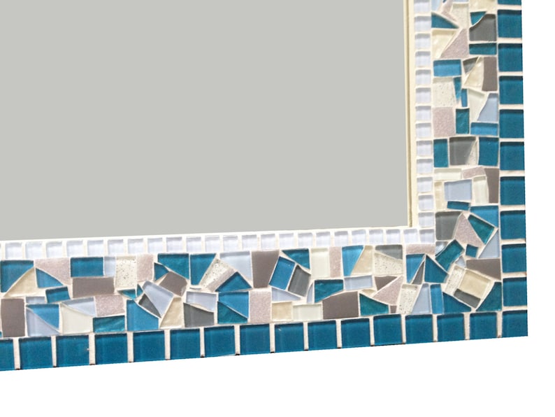May include: A rectangular mirror with a mosaic frame. The frame is made of small, irregular pieces of glass in shades of blue, grey, and white.
