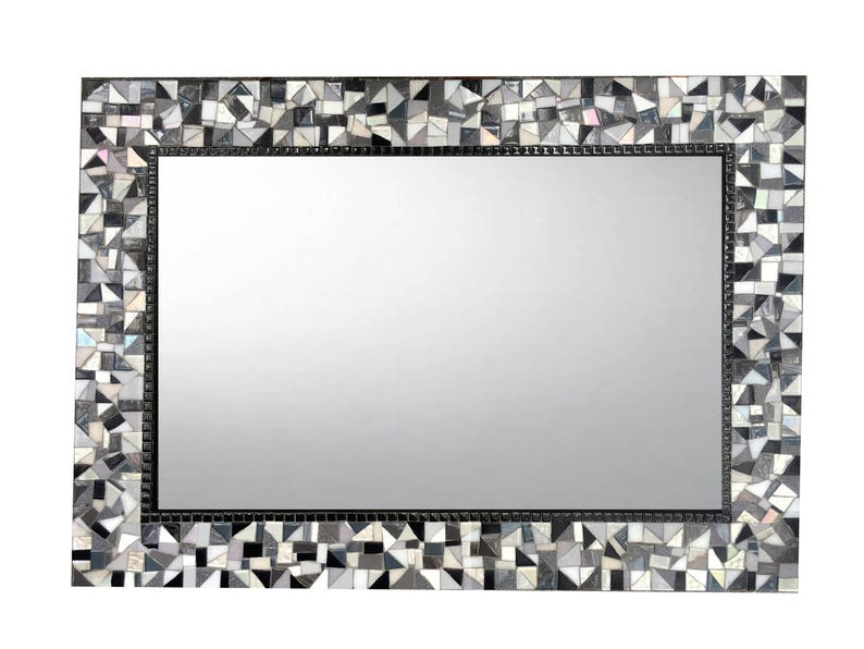 Puede incluir: Un espejo rectangular con un marco de mosaico blanco y negro. El marco est&aacute; hecho de peque&ntilde;os trozos irregulares de vidrio.
