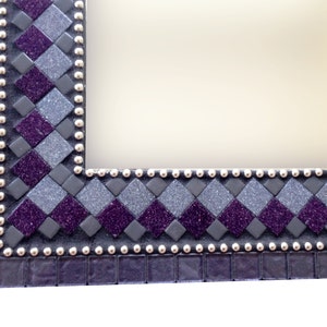 May include: A close-up of a purple and gray mosaic picture frame with a silver beaded border.