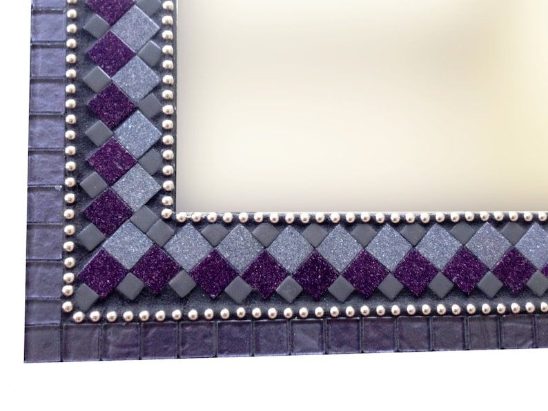 May include: A close-up of a purple and gray mosaic picture frame with a silver beaded border.