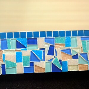 May include: A mosaic tile border featuring a mix of blue, white and light brown tiles. The tiles are arranged in a random pattern.