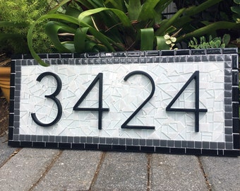 May include: A black and white mosaic house number sign with the number 3424 in black lettering.